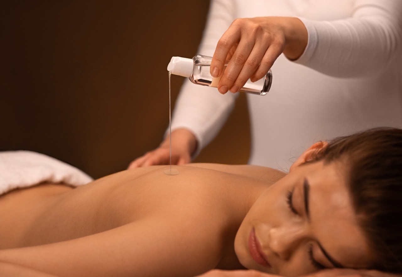 Frau liegt entspannt auf einer Massageliege, während AromaTouch® ätherische Öle sanft auf ihren Rücken aufgetragen werden.